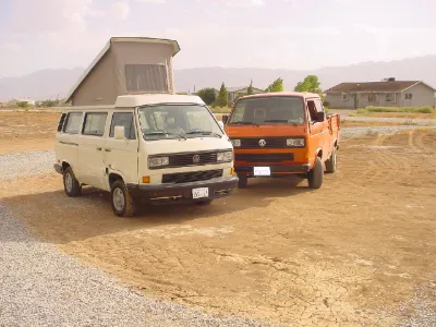 VW Vanagon Westfalia beside an orange T3 double-cab